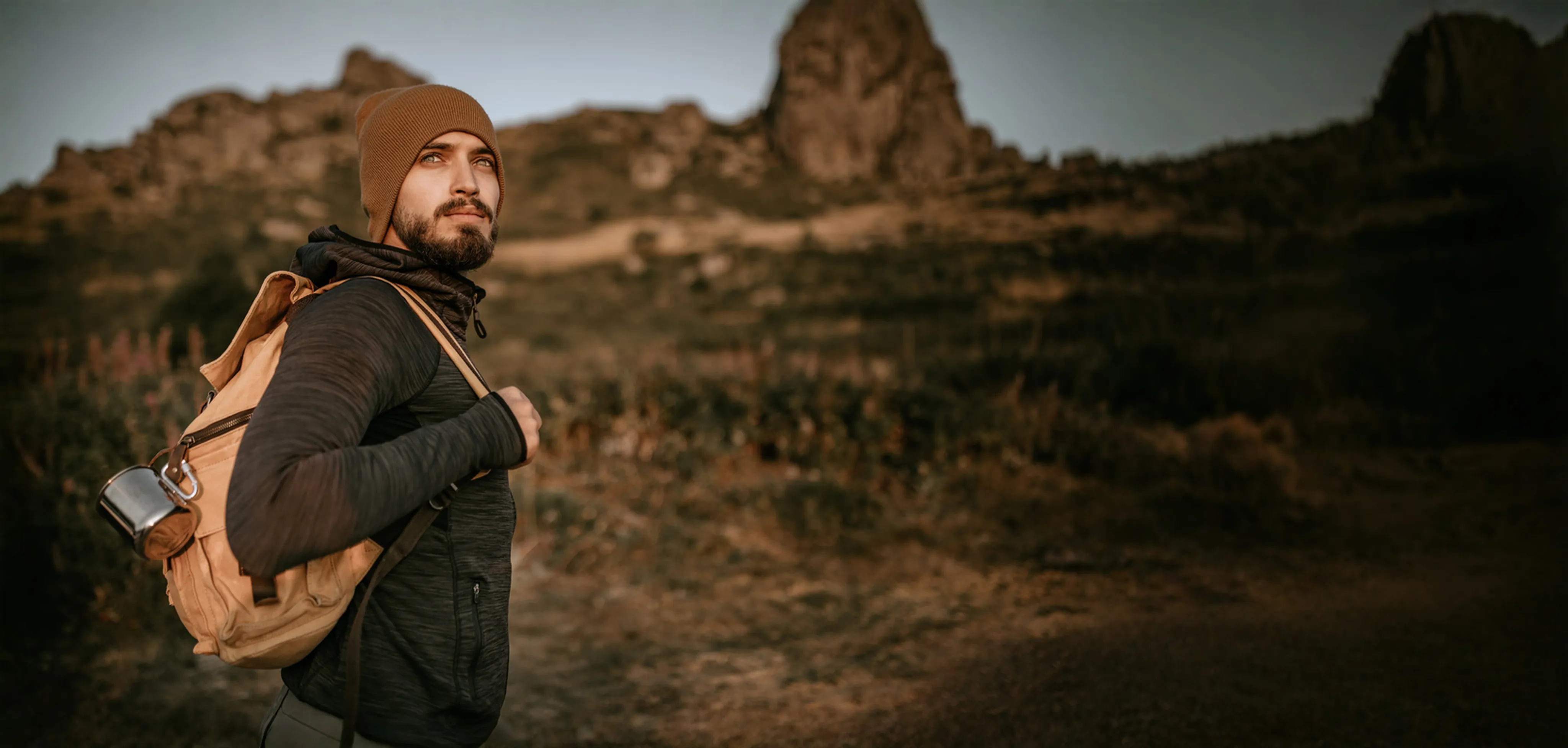 Backpacker pausing on a mountain trail at golden hour