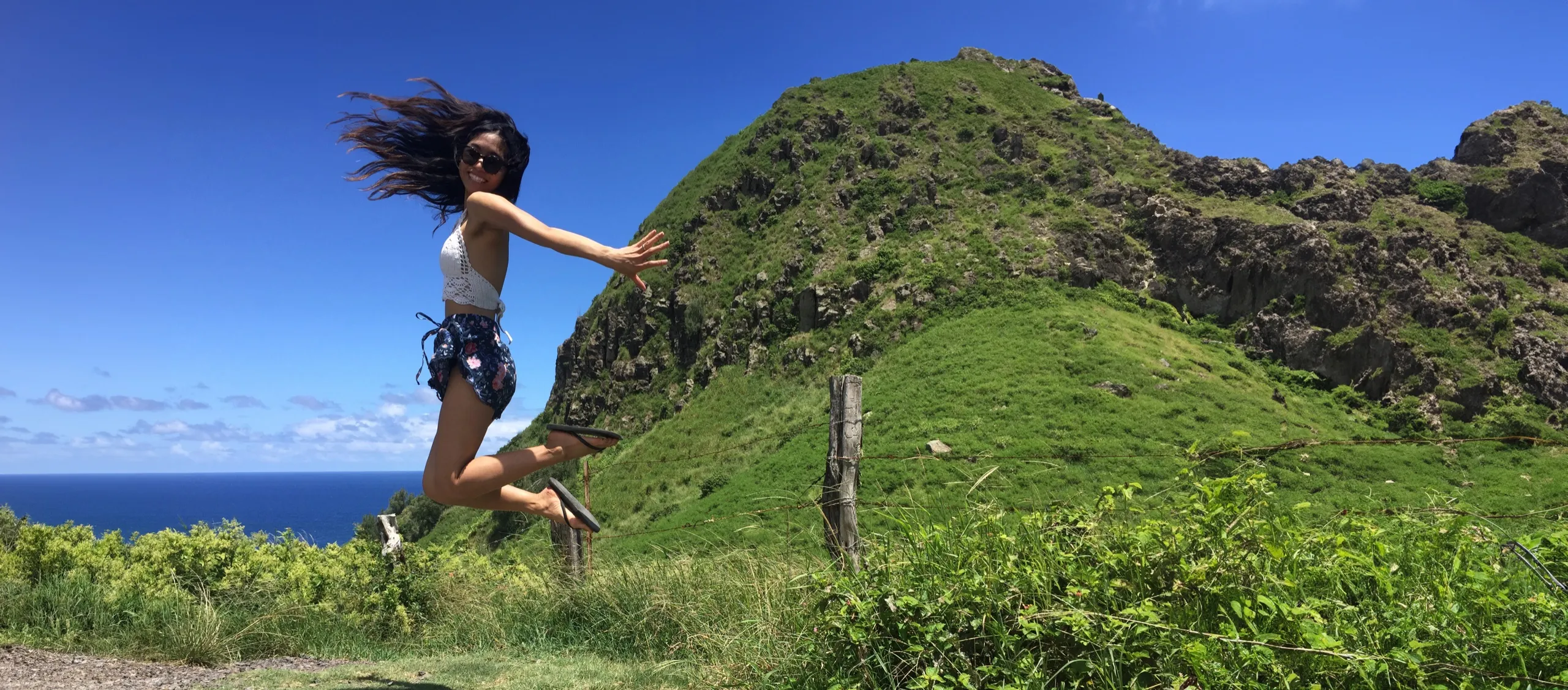 Sabrina Sevilla jumping with joy on a hilltop