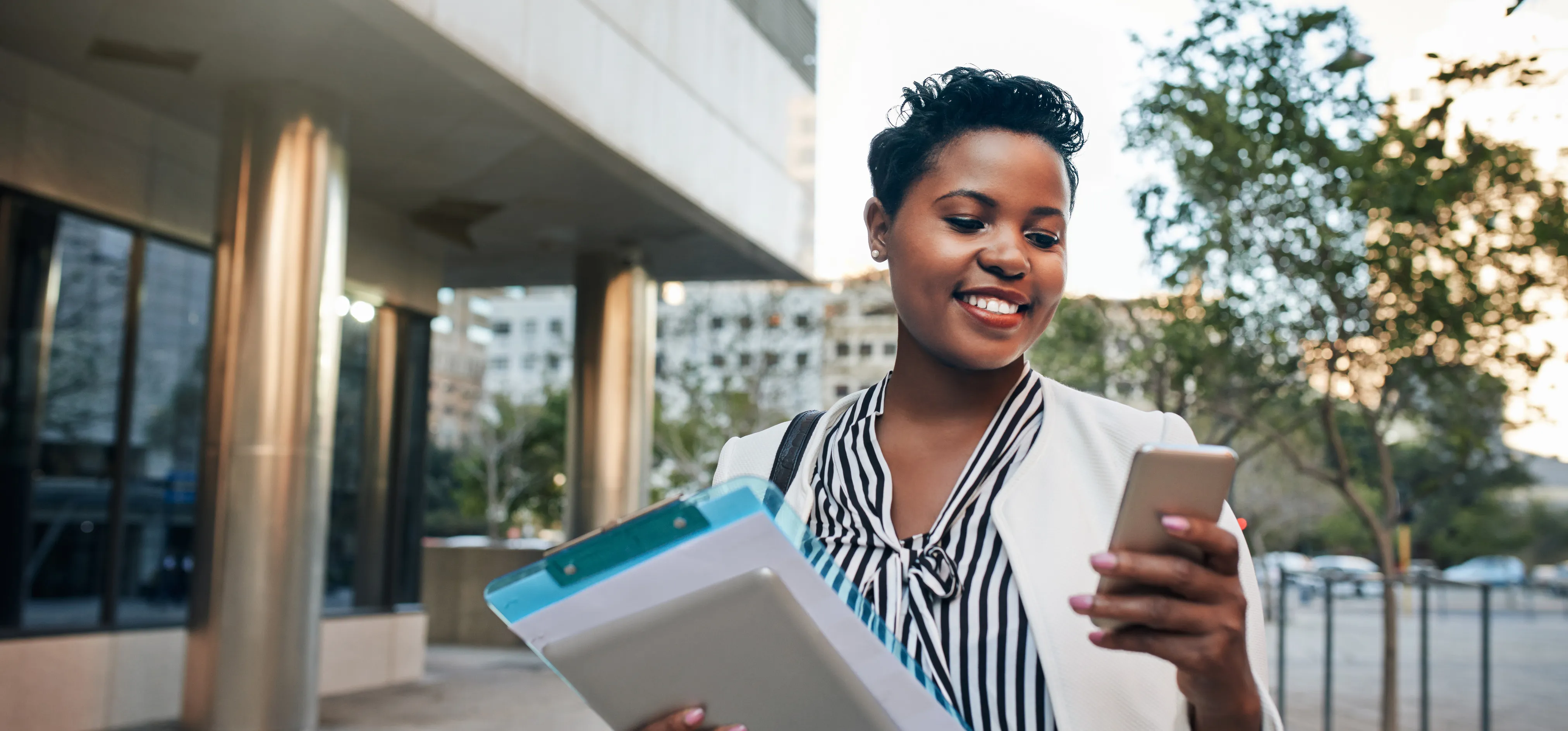 Healthcare professional smiling while holding a phone and clipboard